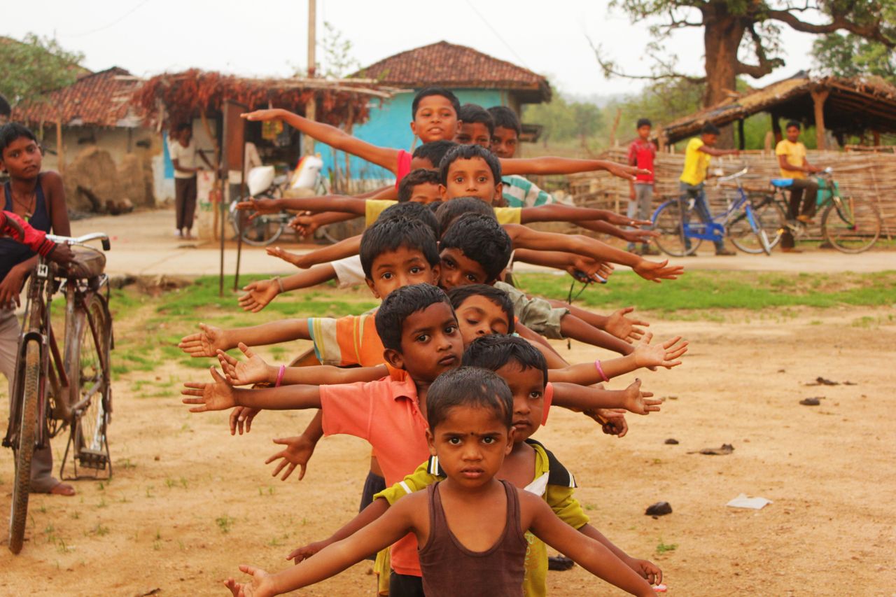 ours-journey A group of smiling Indian boys playing outdoors in a village in Balaghat, showcasing innocence and joy.