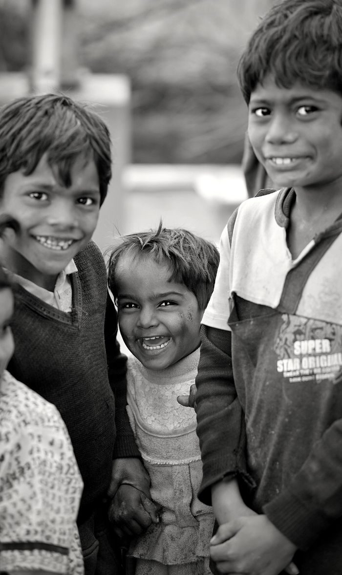about-02 A black-and-white photo capturing the cheerful smiles of three children, radiating joy.