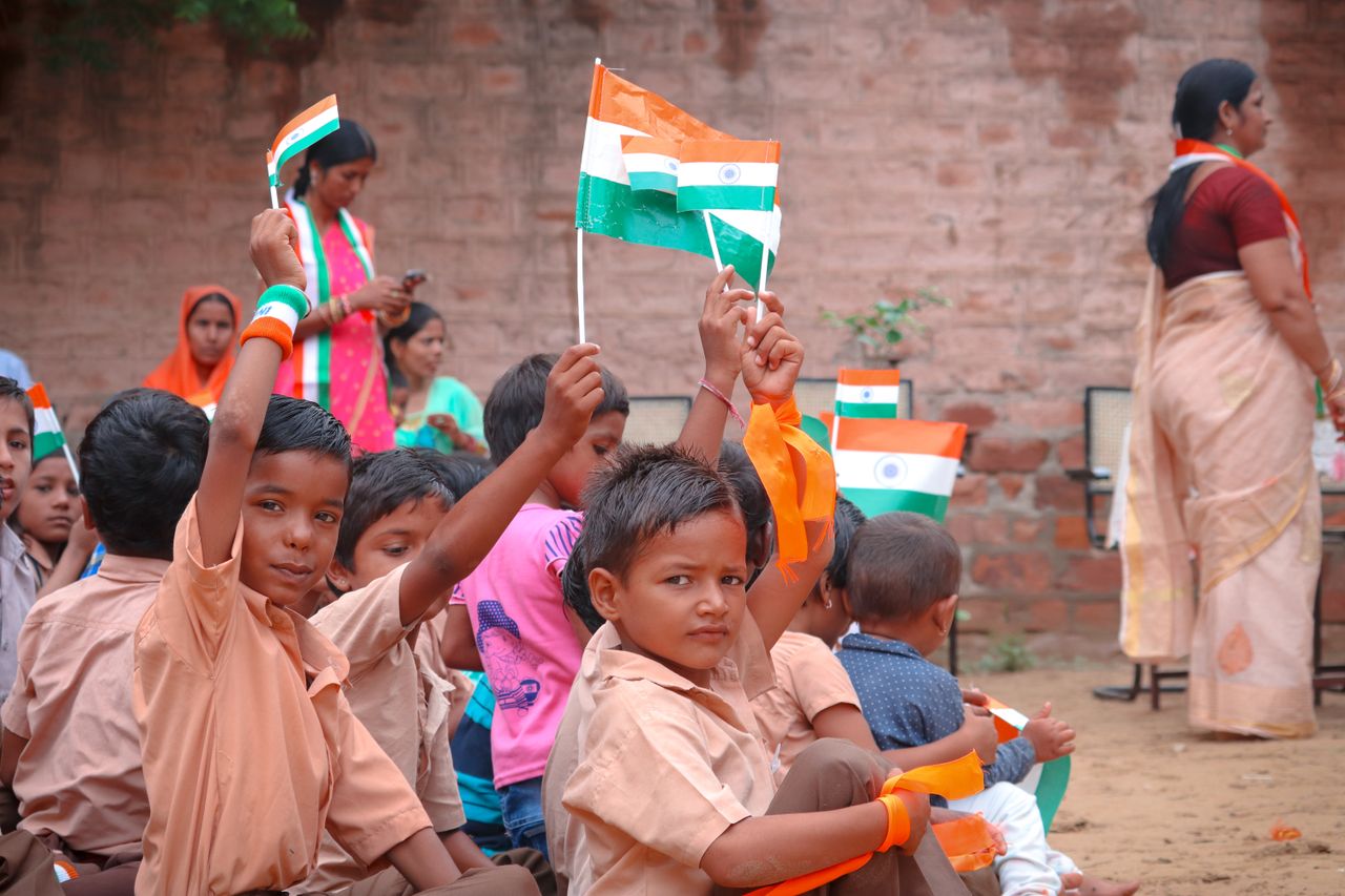 about-img Children in Jodhpur celebrating with Indian flags. Joyous and festive atmosphere outdoors.