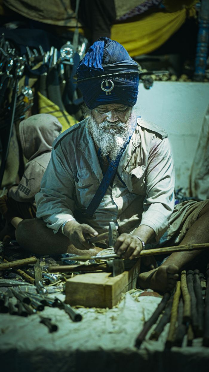 A Nihang Sikh artisan skillfully working on traditional weapons. Cultural and historical craftsmanship at its finest.