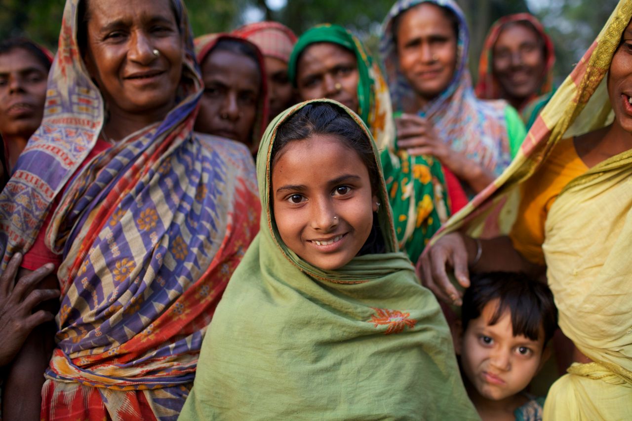 Smiling girl among women showcases empowerment in Kishoreganj, Bangladesh.