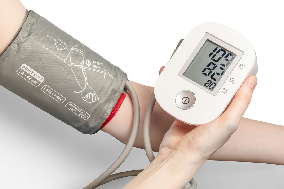 A digital blood pressure monitor showing a reading
