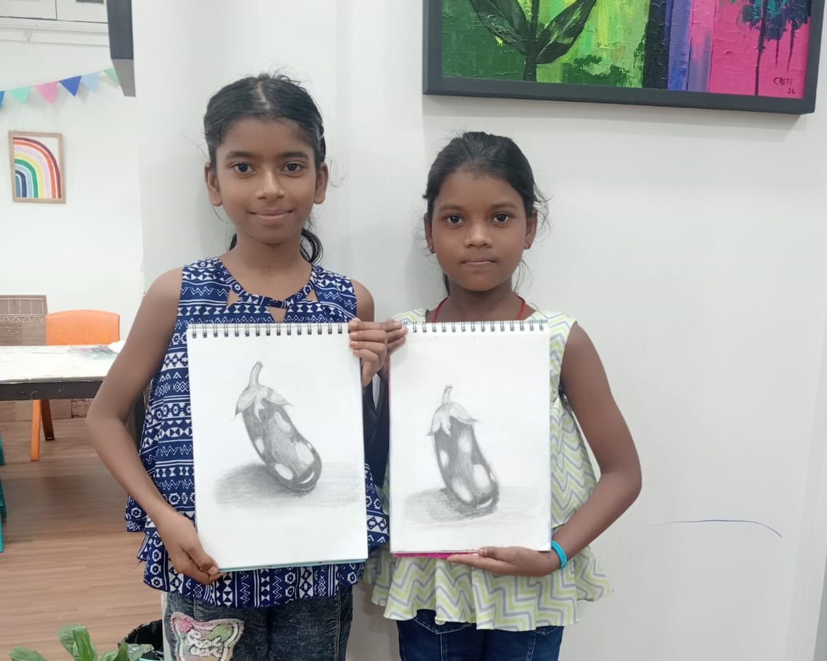 Two girls proudly holding up their pencil sketches