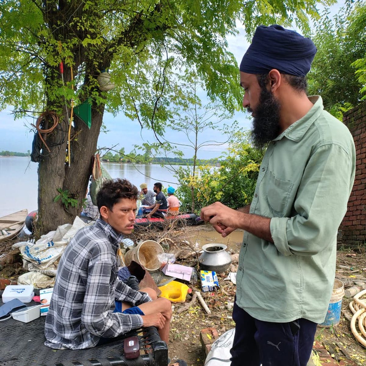 A doctor treating a man in a flood-affected village beside a river