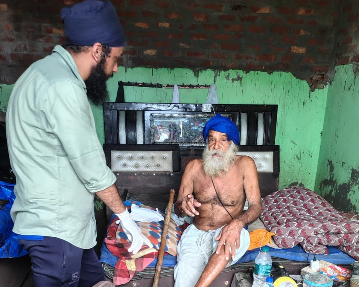 A doctor wearing gloves examining an elderly man at his home